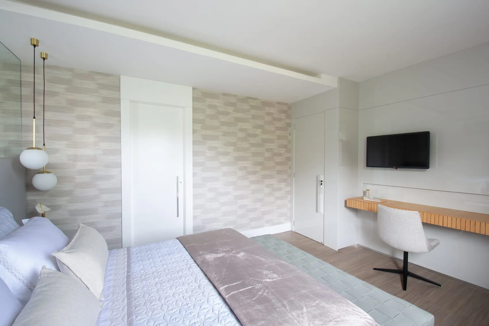 Quarto com papel de parede texturizado, bancada de apoio e televisão na parede