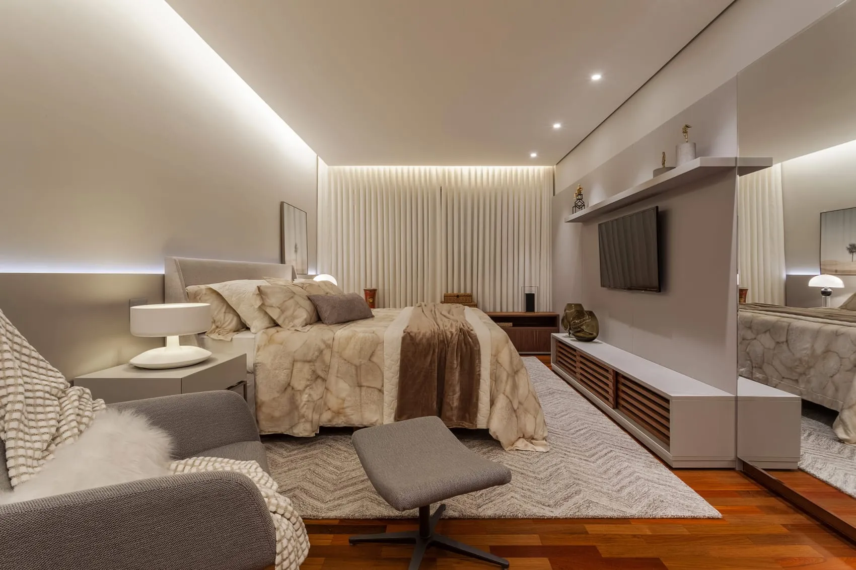 Suíte com painel de TV, recamier aos pés da cama e iluminação embutida