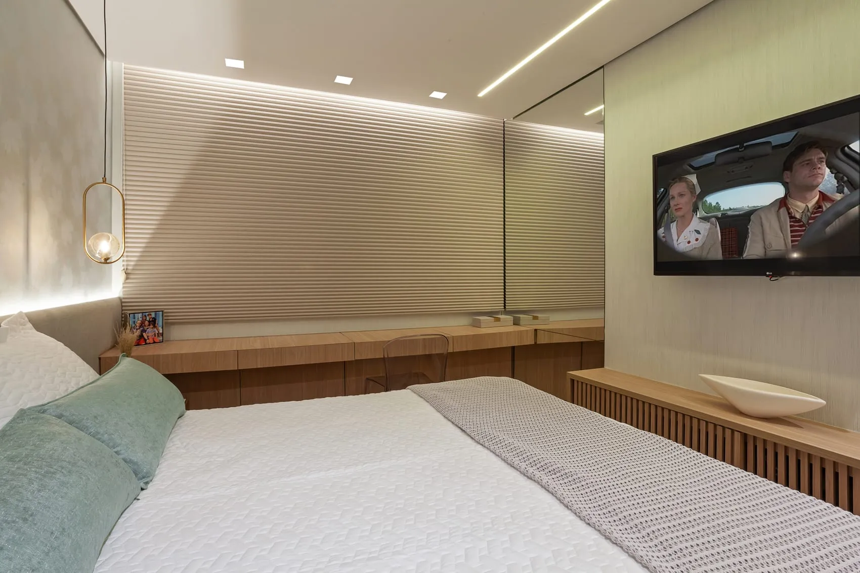 Quarto de casal com televisão, cabeceira ripada e bancada de madeira