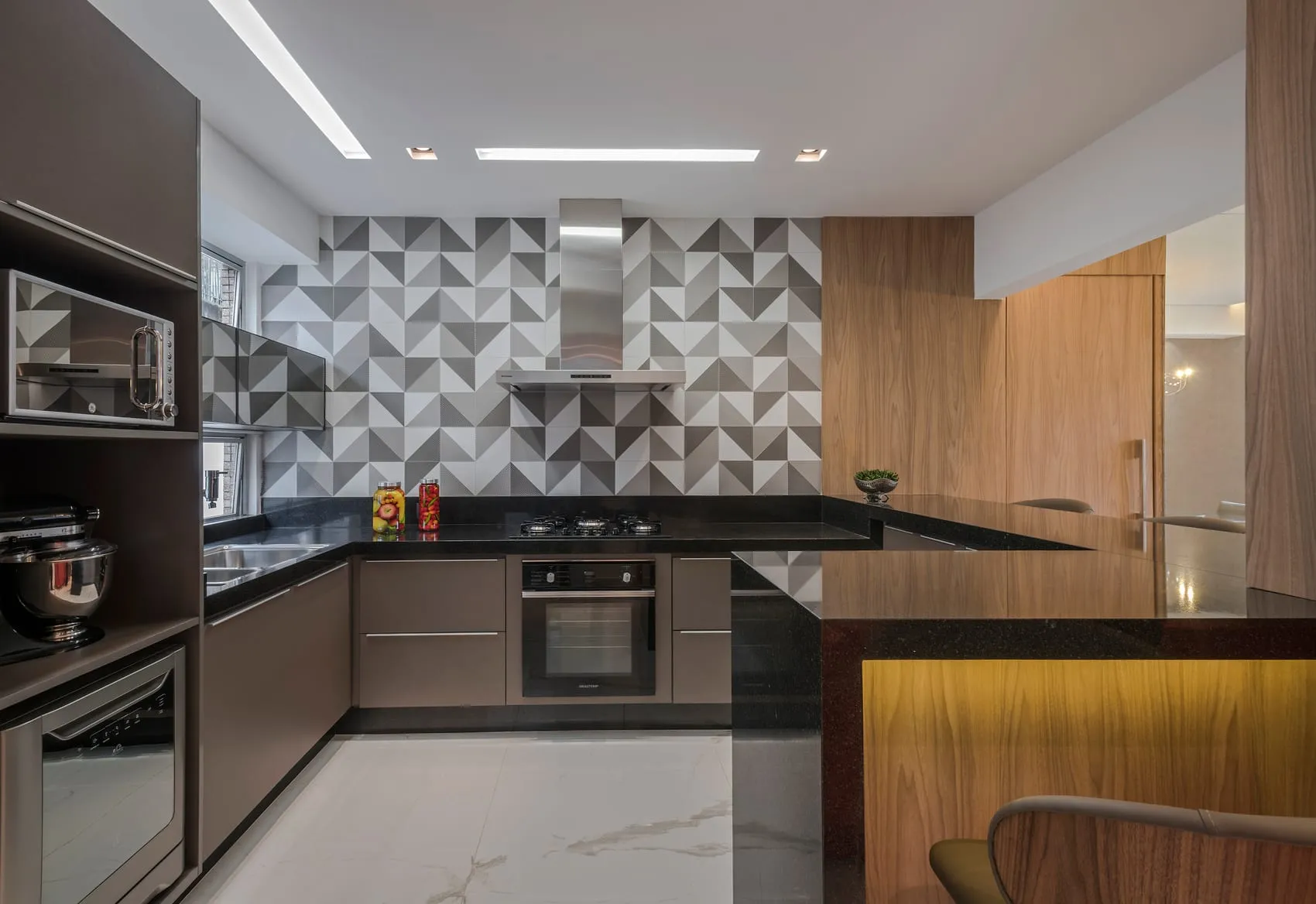 Cozinha com revestimento geométrico em relevo, bancada preta e forno embutido