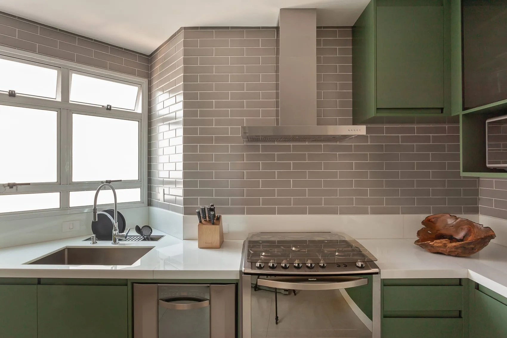 Bancada da cozinha com cuba, cooktop e janela ampla ao fundo