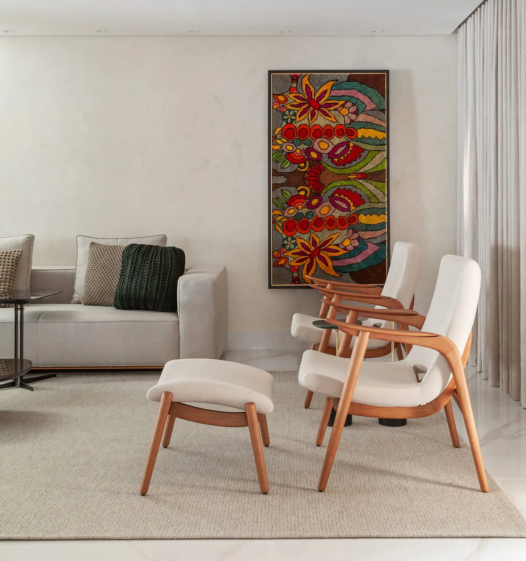 Sala de estar em outro ângulo, com poltronas de madeira e painel colorido na parede