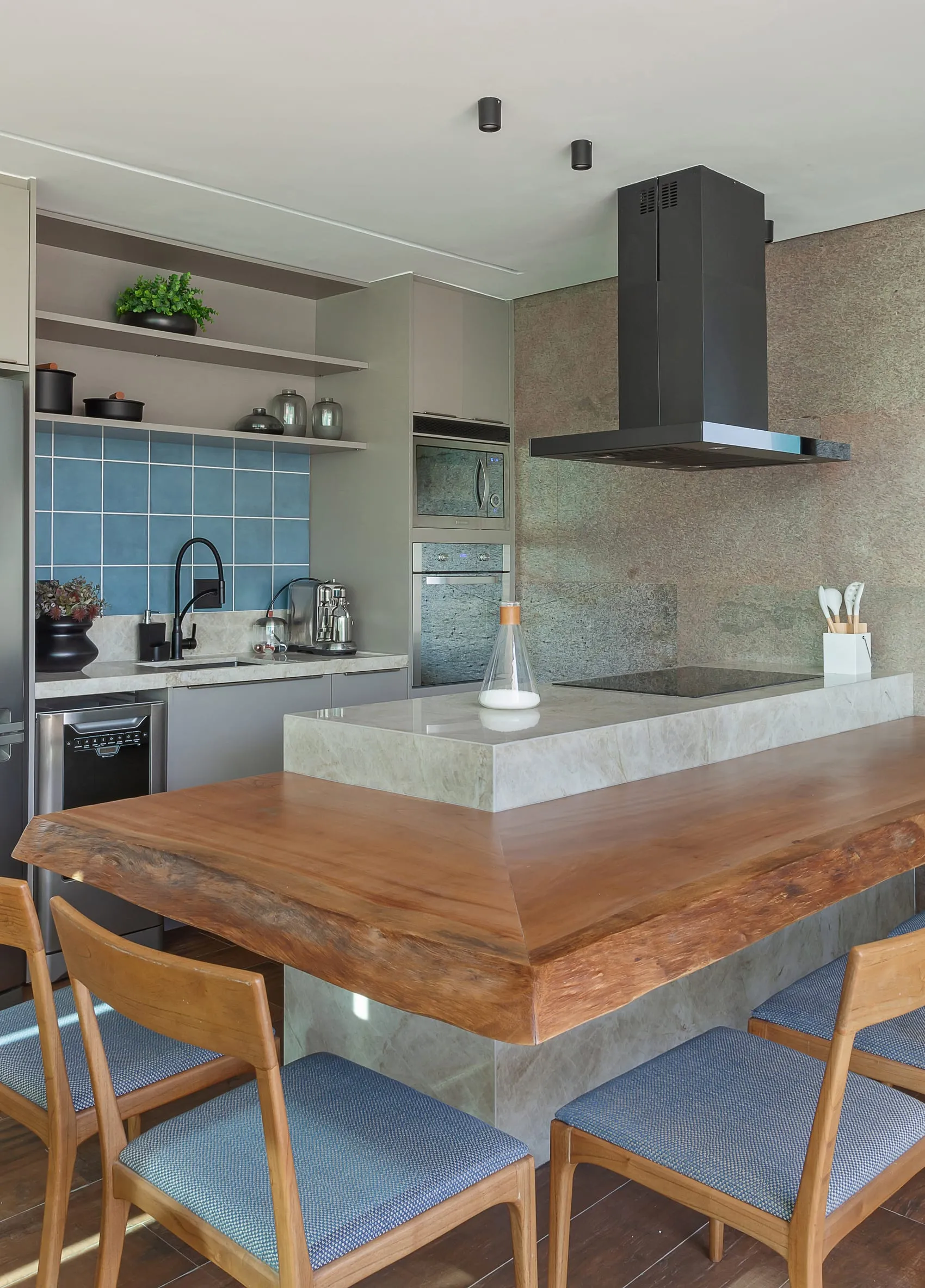 Cozinha com azulejos azuis, coifa e bancada de madeira maciça em primeiro plano