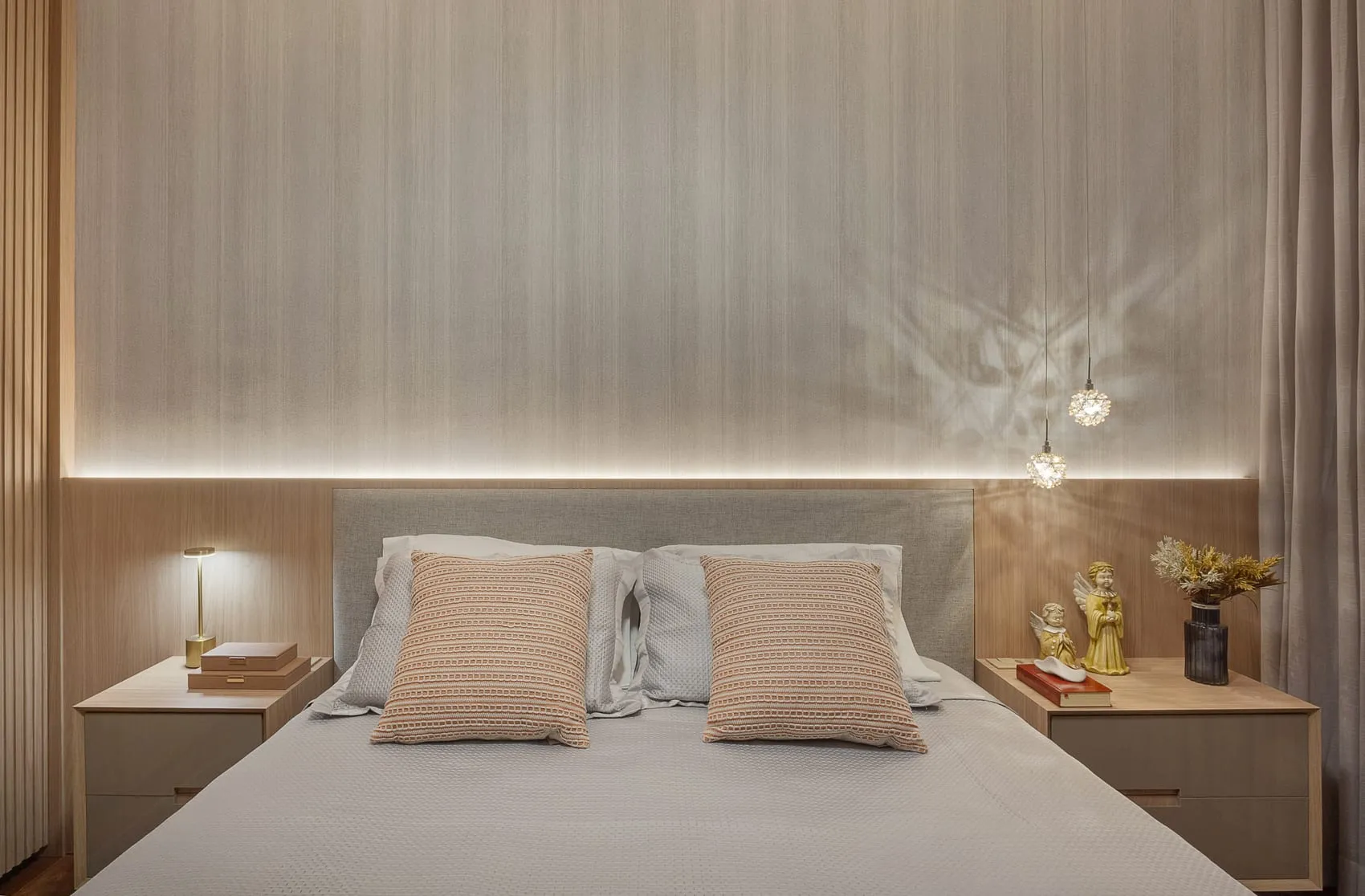 Detalhe da cabeceira do quarto com pendente fino e luminária de mesa