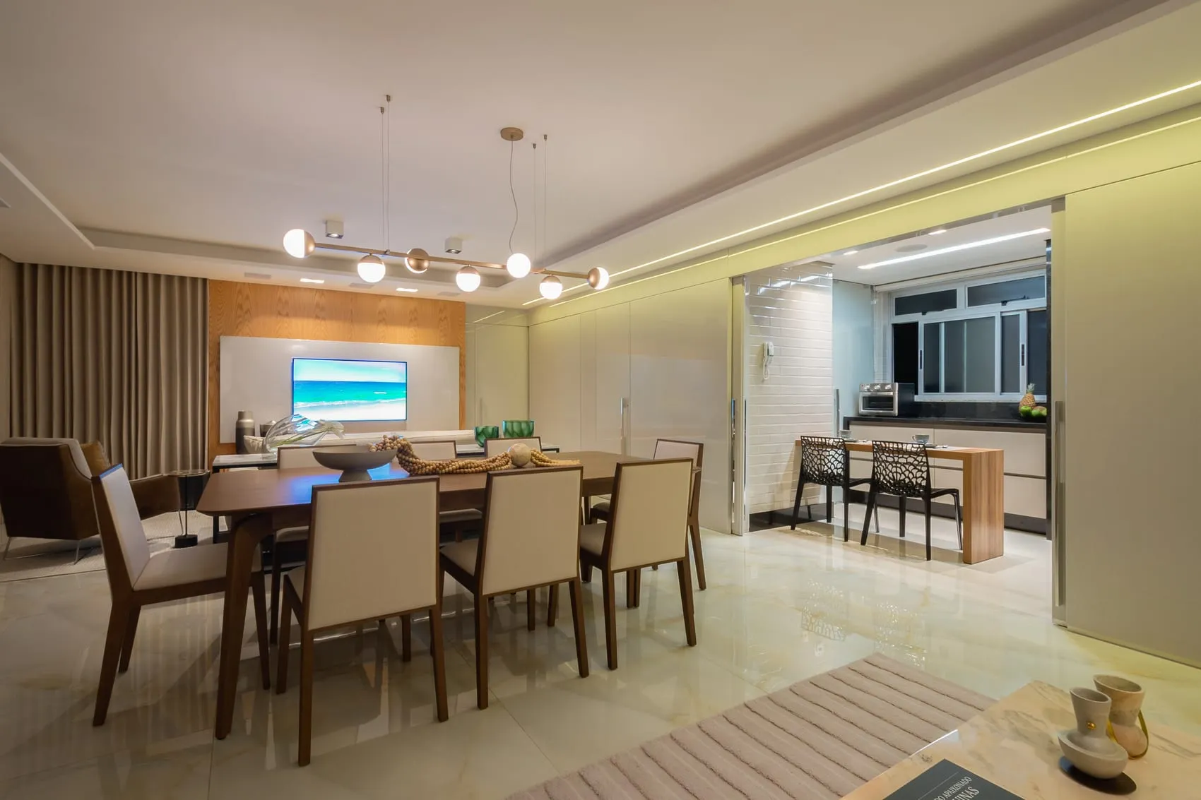 Sala de jantar vista da entrada, com tapete listrado e cozinha ao fundo