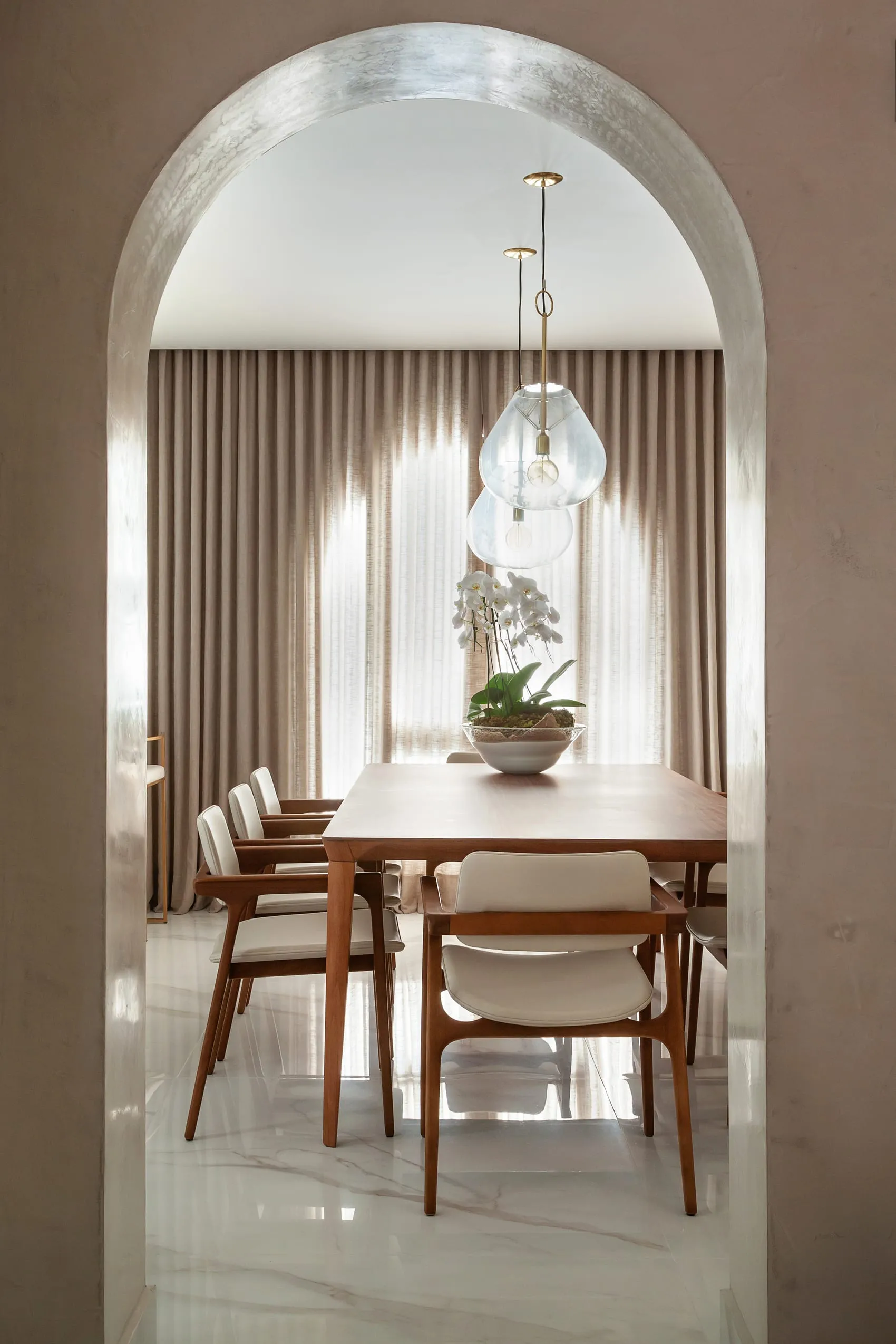 Sala de jantar com mesa retangular, pendente de vidro e cortina clara