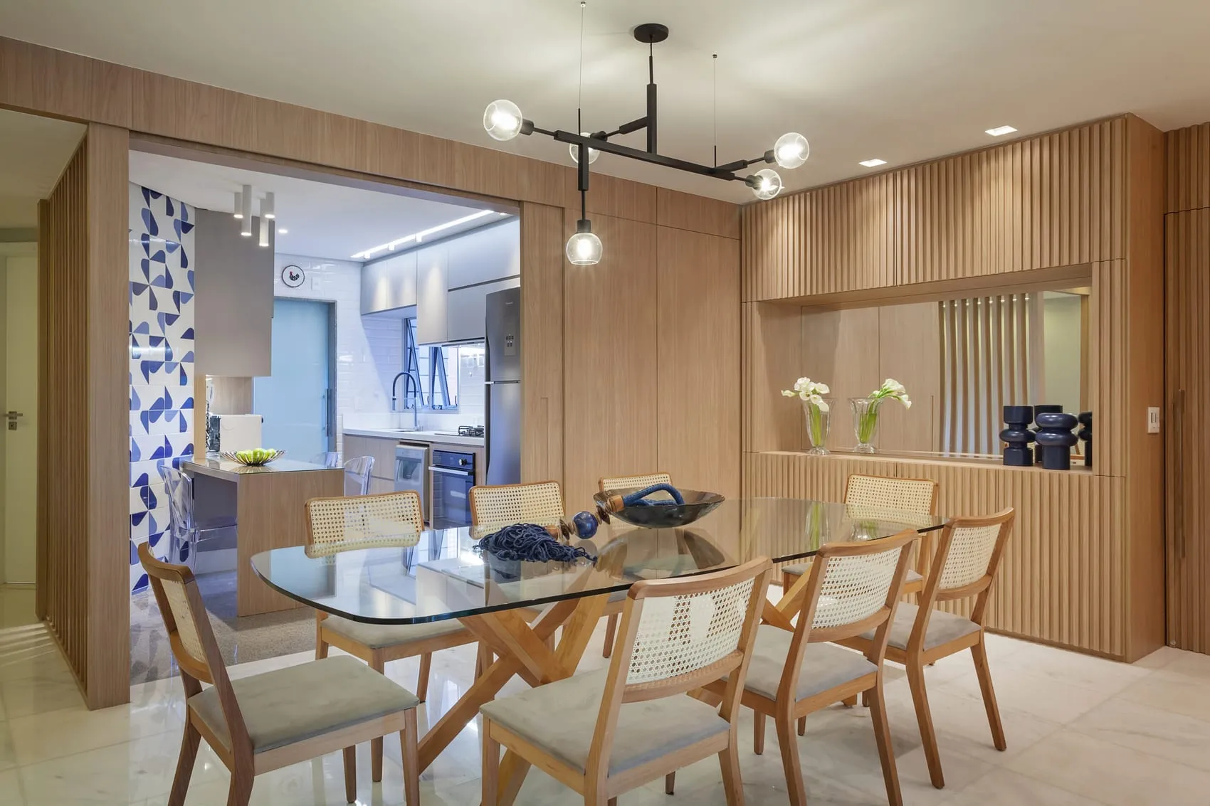 Sala de jantar com cozinha ao fundo e cortina estampada em azul