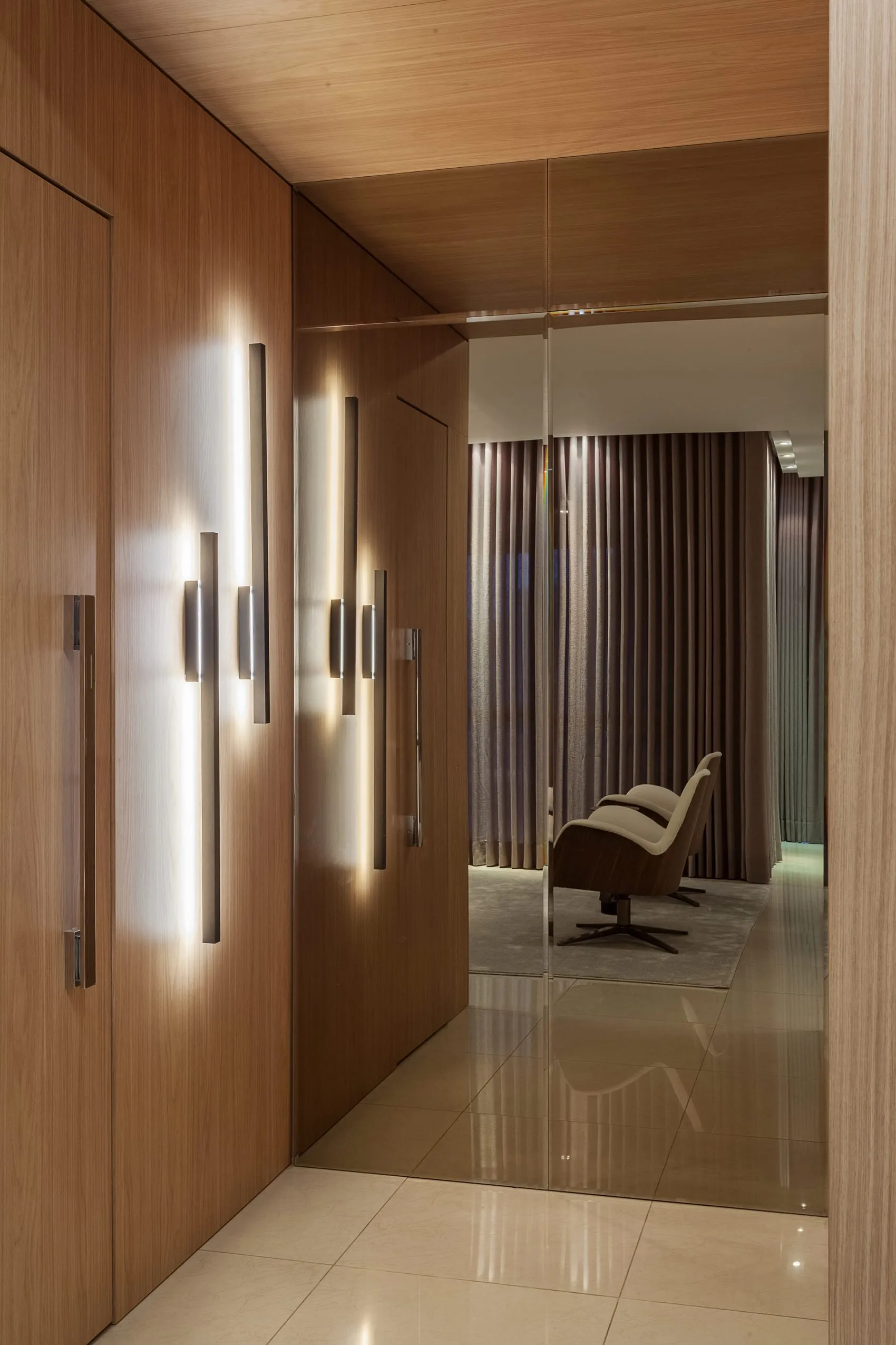 Hall interno com arandelas verticais e marcenaria em madeira