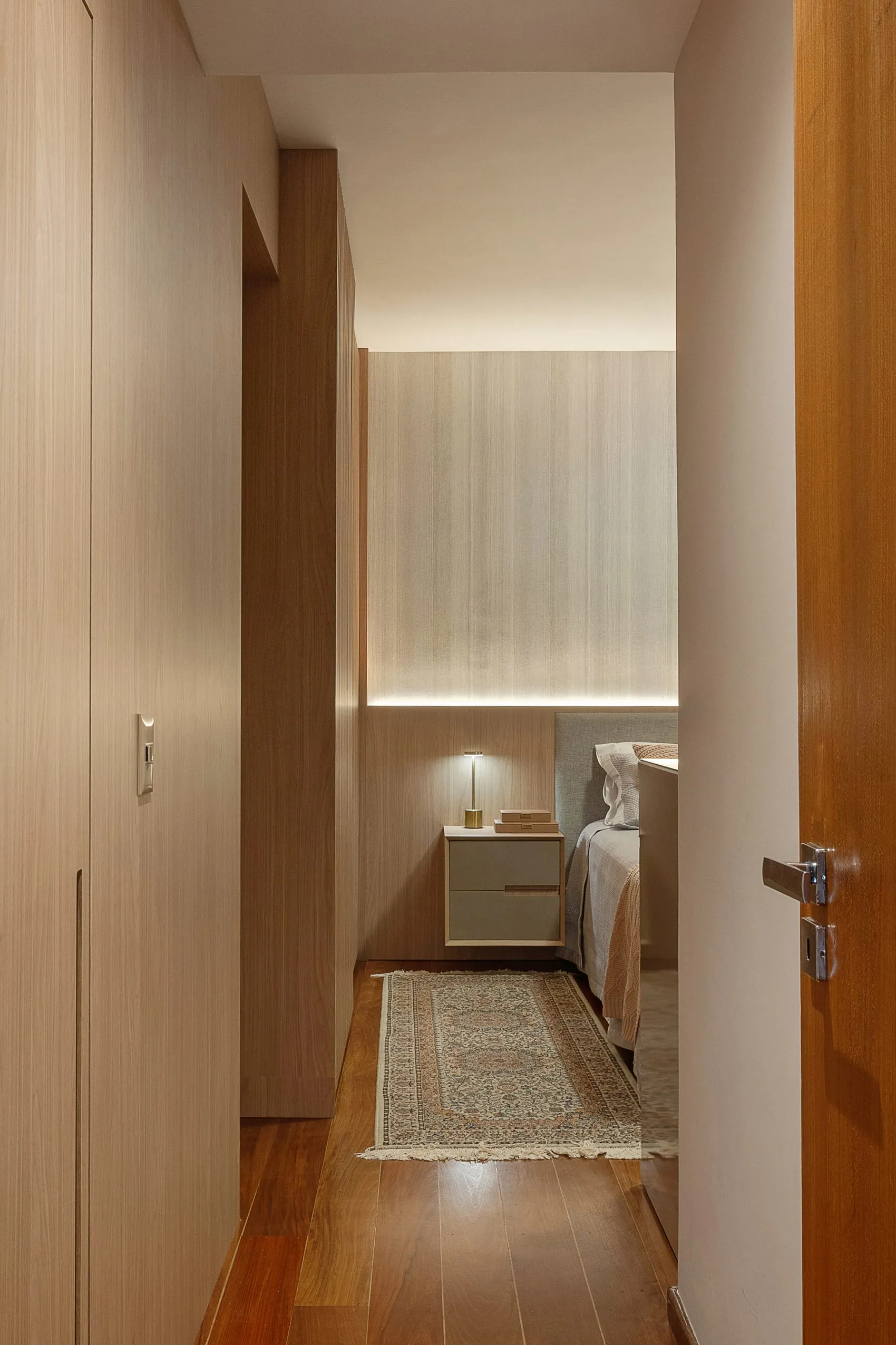 Corredor de acesso ao quarto com marcenaria clara e closet embutido