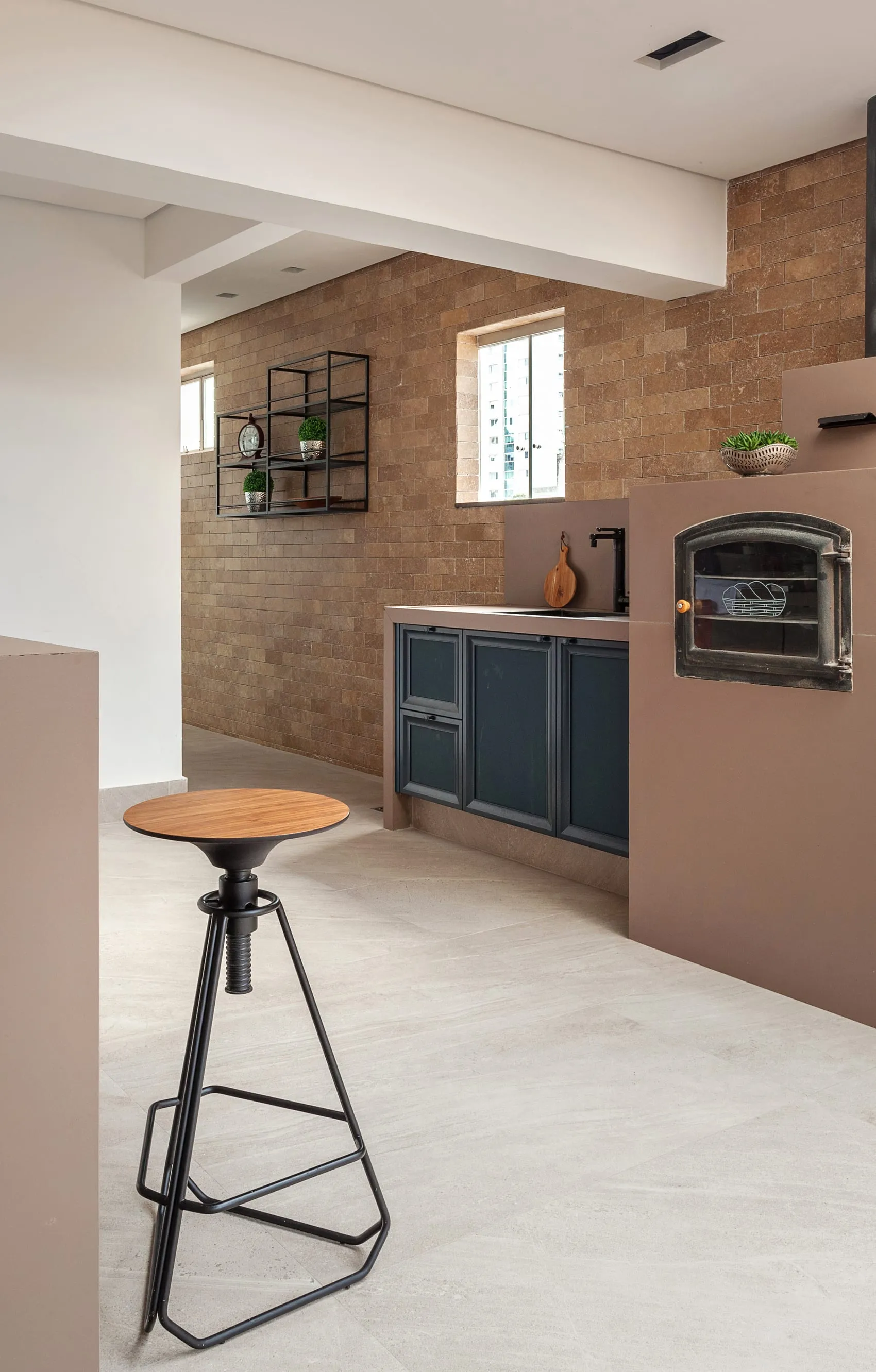 Área de churrasqueira com forno de pizza, bancada azul e revestimento de tijolo