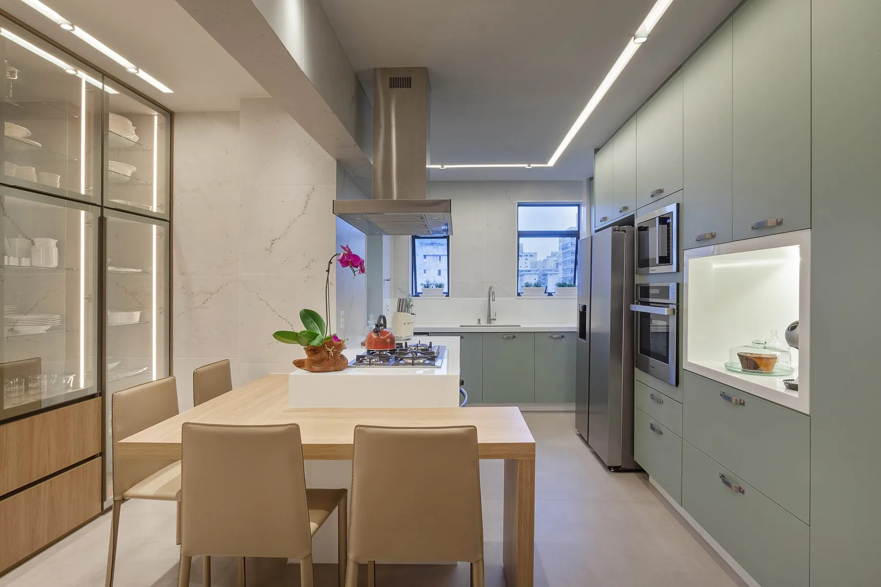 Cozinha reformada com marcenaria verde, ilha central com mesa integrada e iluminação embutida