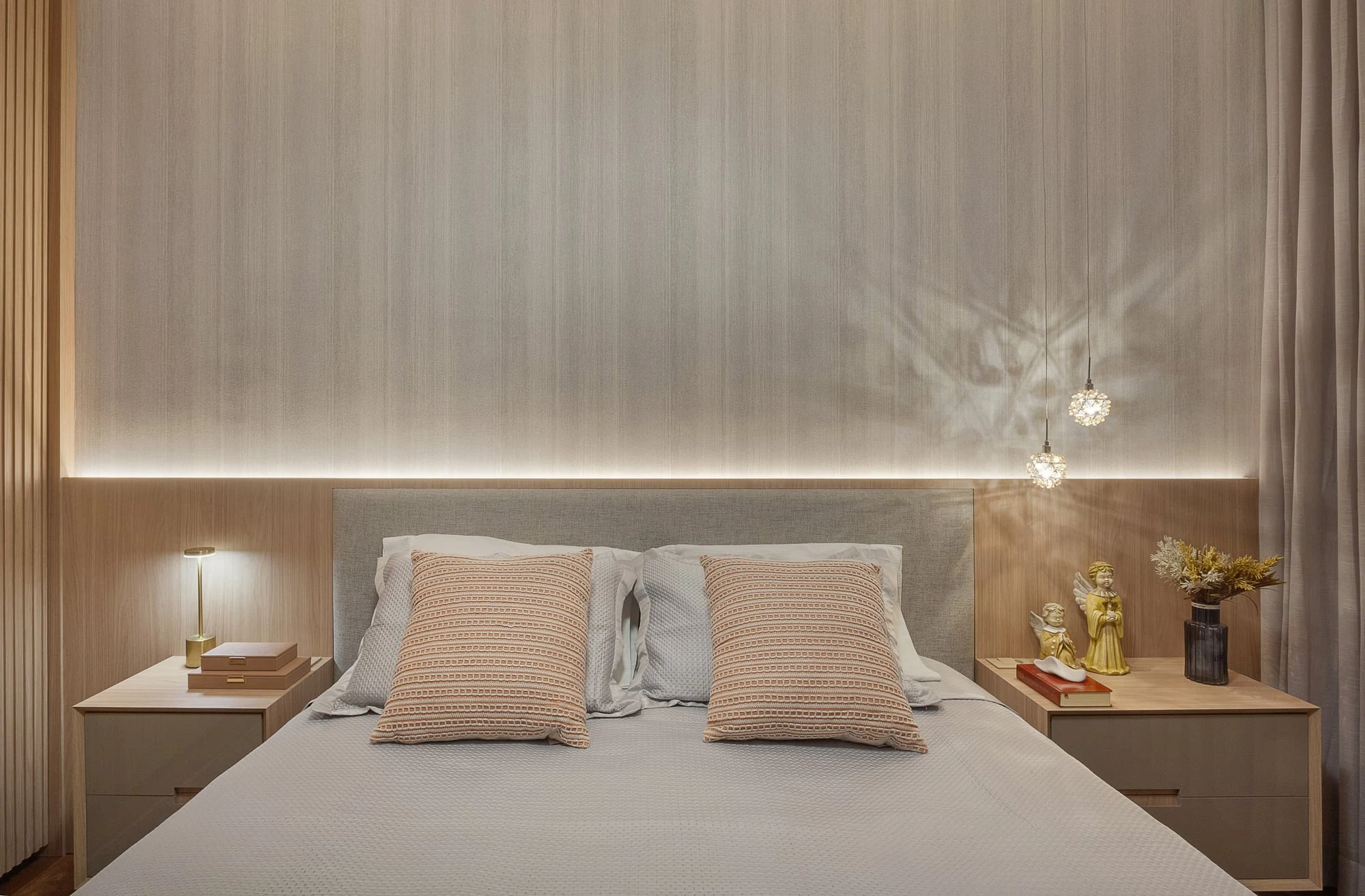Quarto de casal com iluminação indireta, cabeceira estofada e roupa de cama em tons neutros
