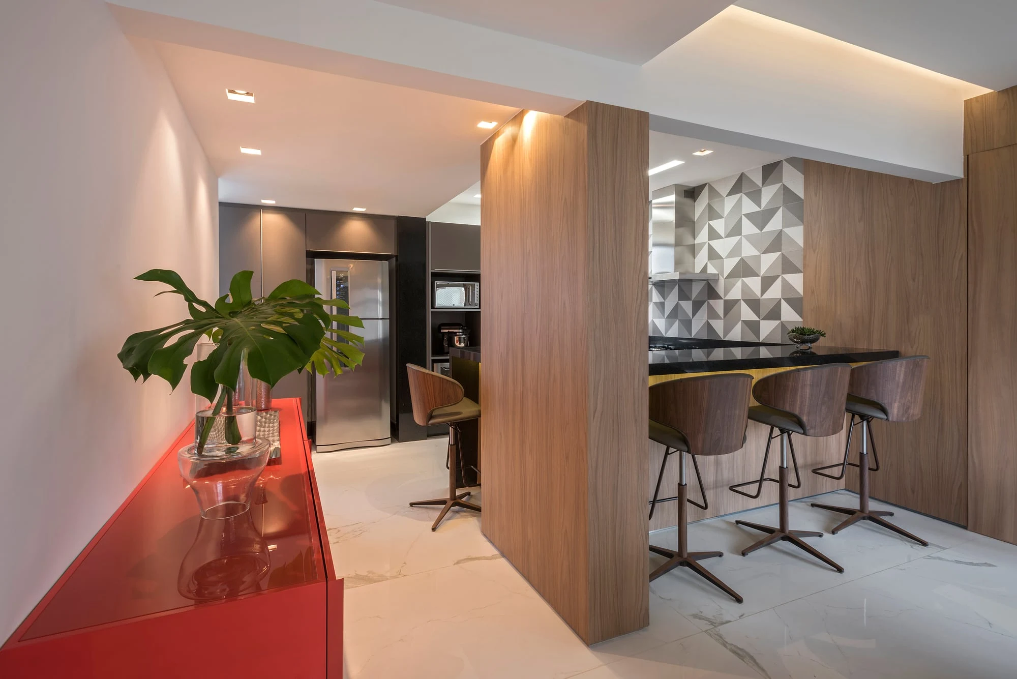 Espaço gourmet integrado com bancada, banquetas e revestimento em madeira